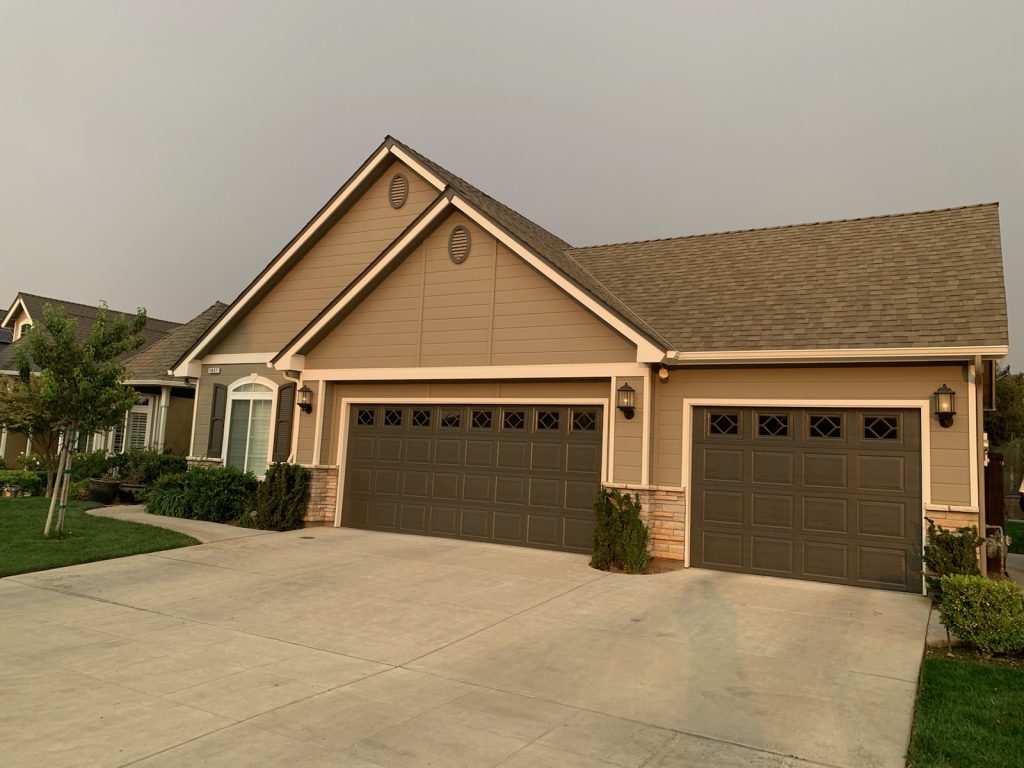 Beige house with a dark garage door, white trim, and a front walk
