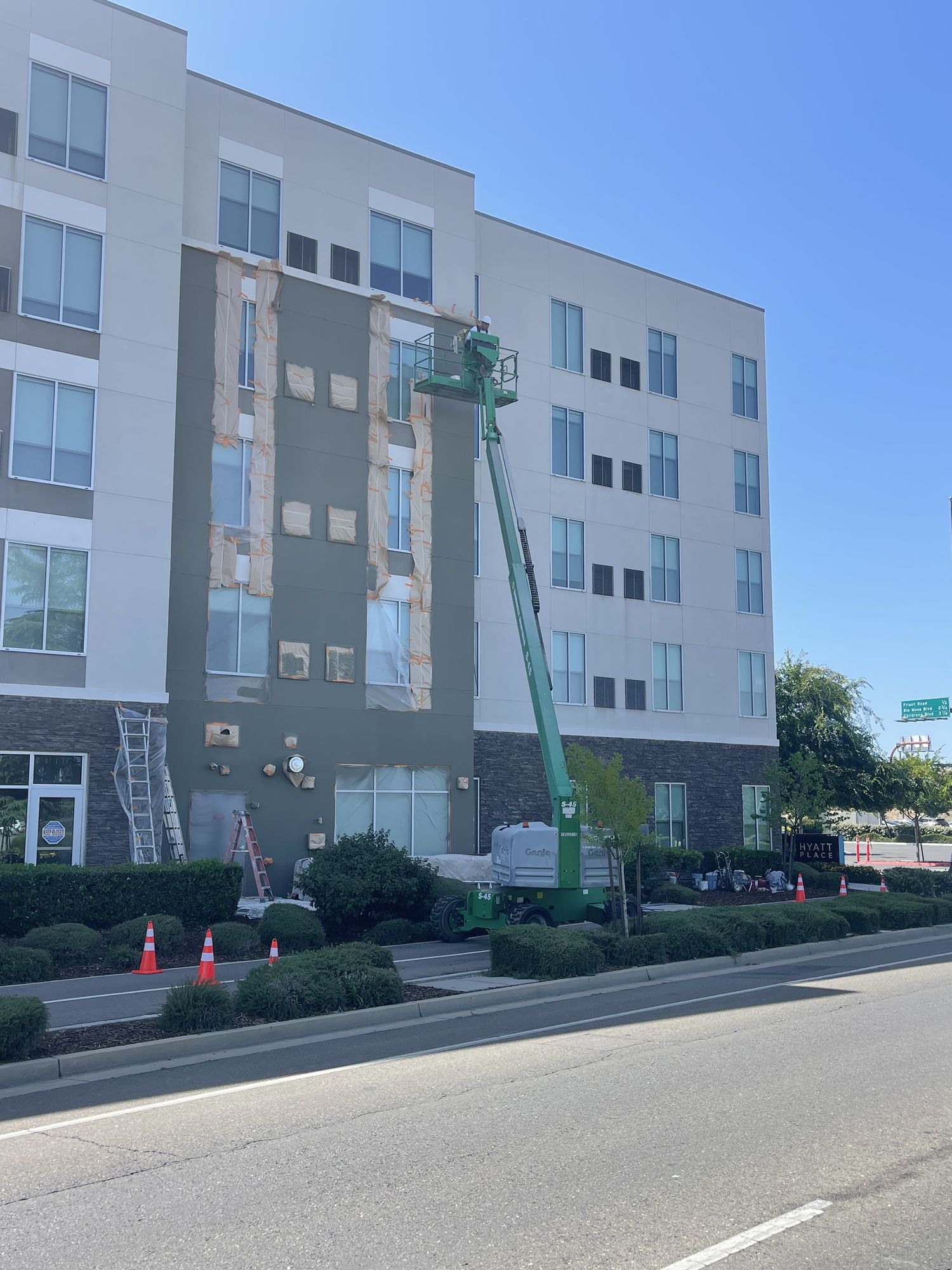 Multi-story hotel facade during exterior painting, windows masked