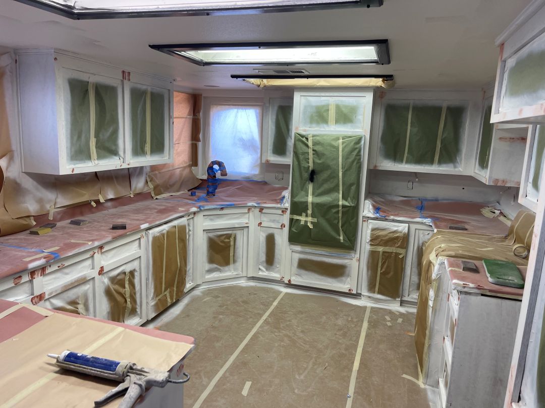 Kitchen cabinets masked with plastic and tape before painting