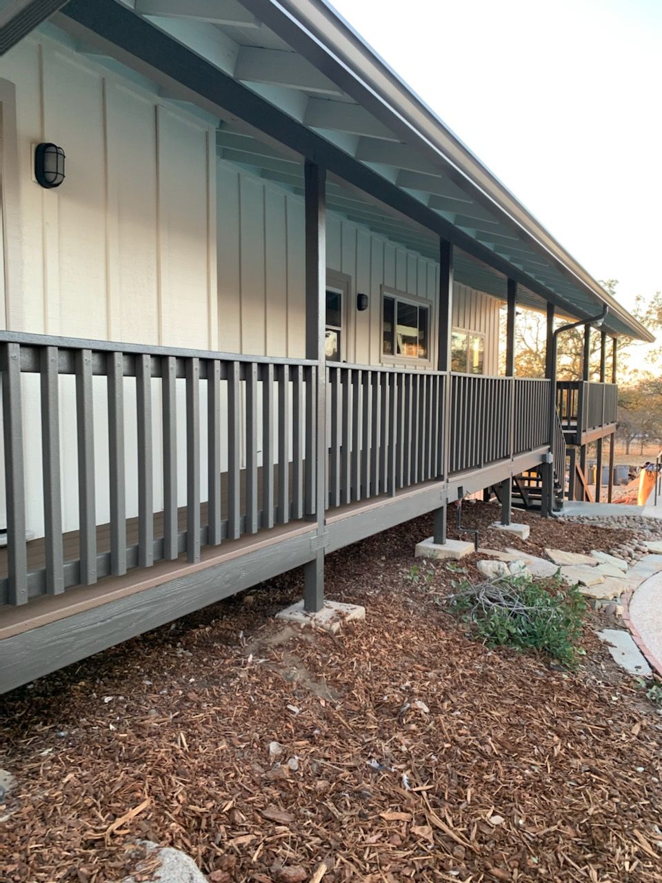 Long porch with a painted gray rail and cream siding