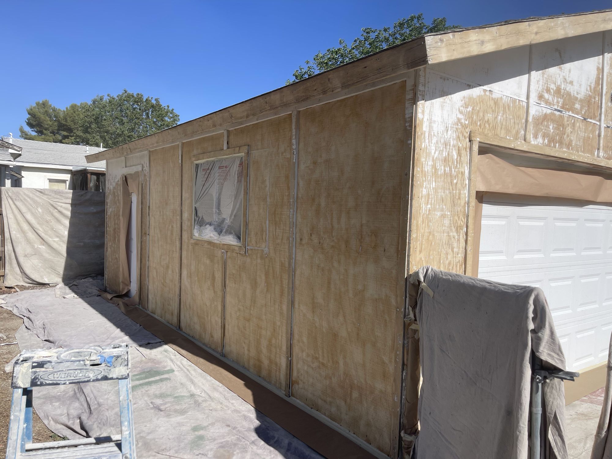 Exterior wall masked and prepped down to bare substrate before paint