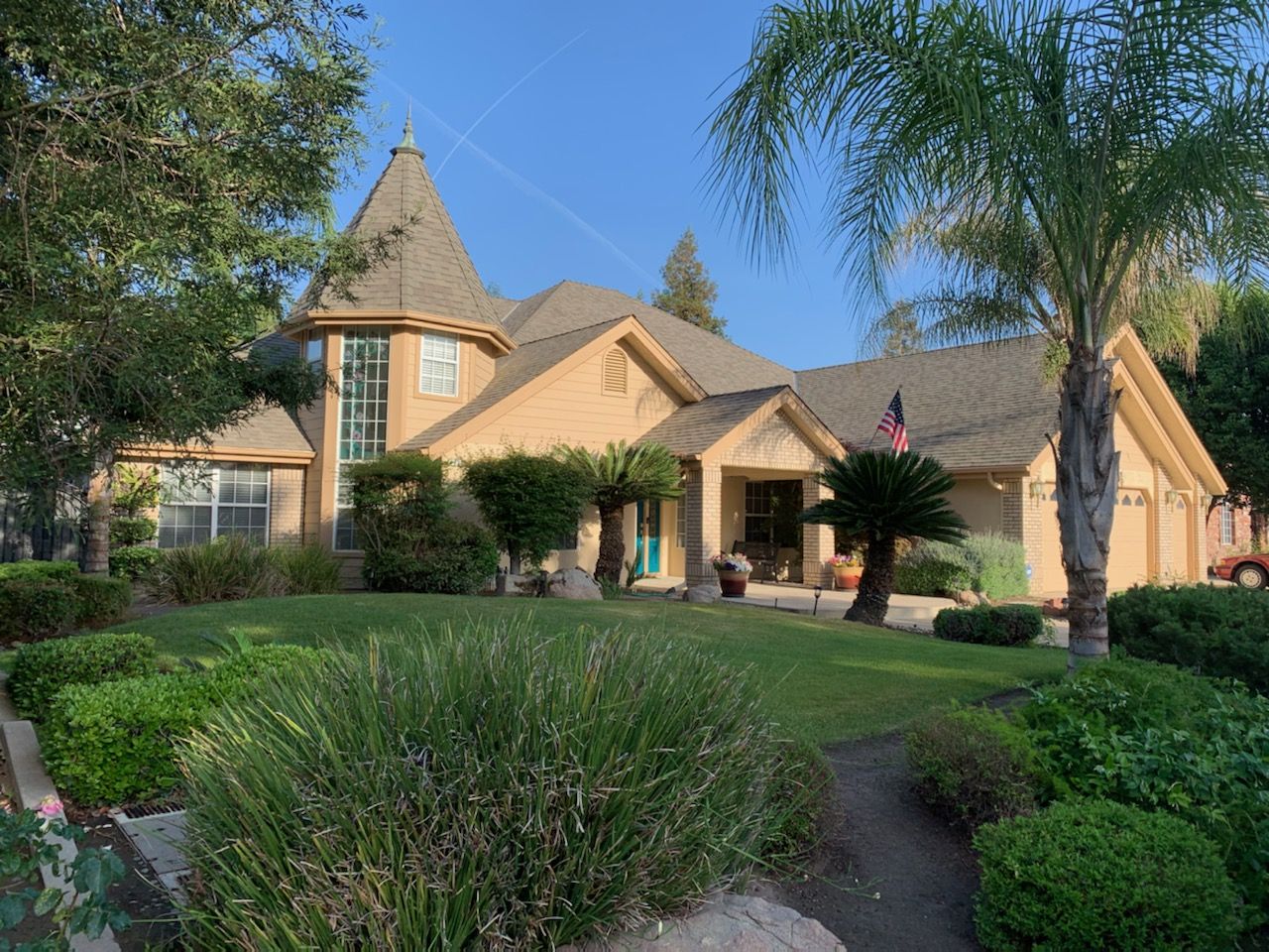 Tan estate home with a turret, tile accents, and a painted entry