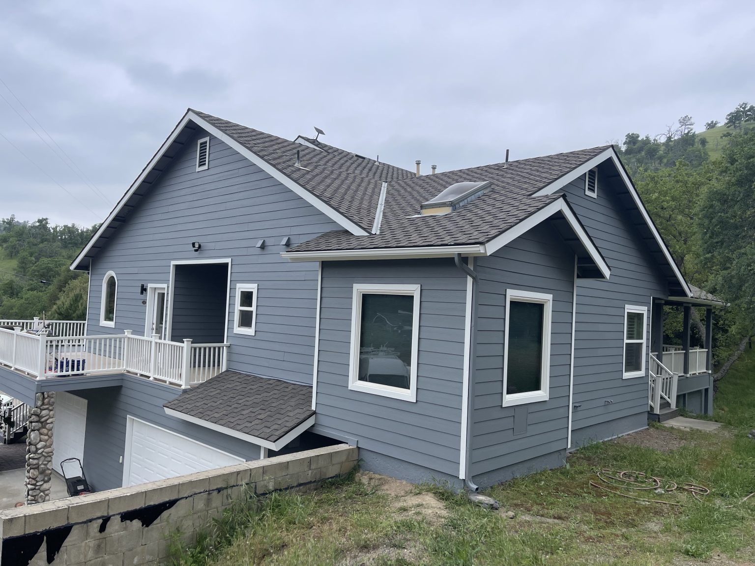 Gray Tollhouse house with white trim and a deck, hills behind it